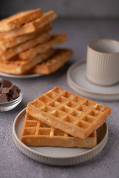 istock Delicious stacked waffles on plates with crispy texture accompanied by chocolate pieces and elegant cups, perfect for breakfast or brunch inspiration and dessert enthusiasts 2193269679