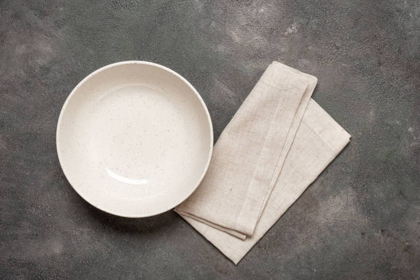 istock Empty beige bowl with linen napkin on dark grunge background, top view 2193273265