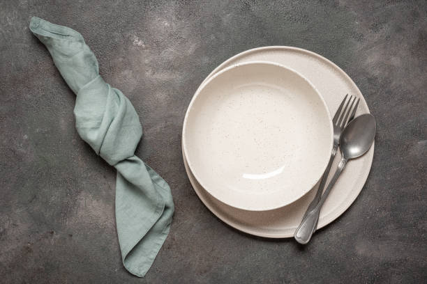 istock Two empty plates with cutlery and linen napkin on dark rustic background, top view, minimal table setting 2193273270