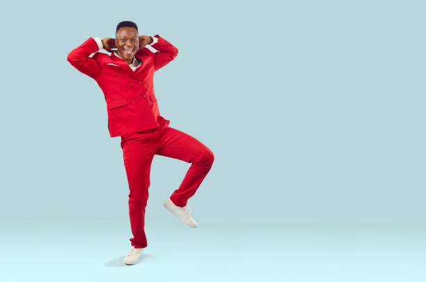 istock Happy excited African American man in red suit dancing on light blue copy space background 2193275680