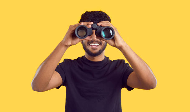 istock Happy ethnic man looking through binoculars looking for profitable advertising offers. 2193276649