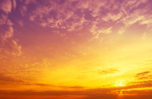 Background sky view of the breathtaking beauty of nature's canvas as the sky transforms into a mesmerizing display of blue and orange hues at sunset. Sunrays cascade through the clouds from the sun, illuminating the landscape with a warm, golden glow. This panoramic view captures the ethereal beauty of the evening sky, inviting viewers to immerse themselves in the tranquil and dramatic atmosphere of this captivating scene