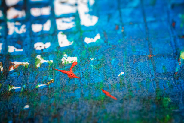 Close-up of a blue textured surface with a speckled pattern of small dots and imperfections. The image highlights the rough texture and varied tones of blue, creating an abstract and visually interesting composition.