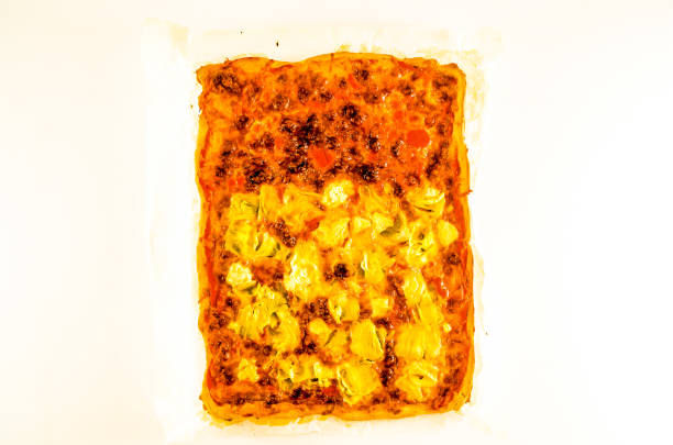 A pizza with cheese and meat toppings is sitting on a white plate. The pizza is covered in cheese and has a variety of toppings, including meat and vegetables
