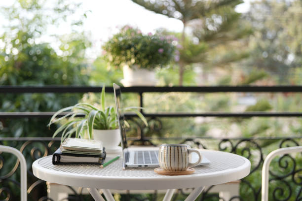 istock Laptop side view and coffee cup with notebooks on white table balcony outdoor 2193281414