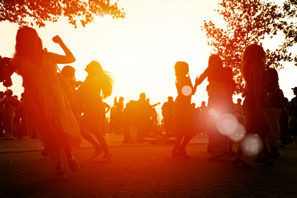 Sunset Celebration at Templo de Debod in Madrid, Spain. Silhouettes of people dancing and enjoying the golden hour near Templo de Debod, creating a vibrant and joyous atmosphere under the warm glow of the setting sun.