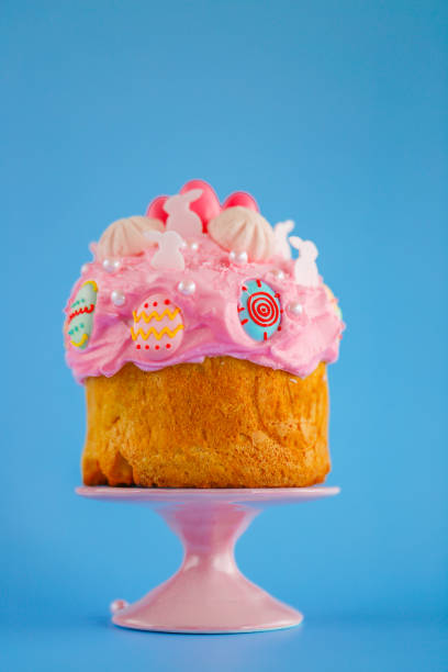 Easter Themed Cake Decoration with Pink Frosting on a pink ceramic stand on a blue background