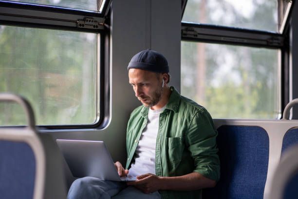 istock Focused man freelancer remote works on laptop riding in electric train using internet in train car. 2193282766