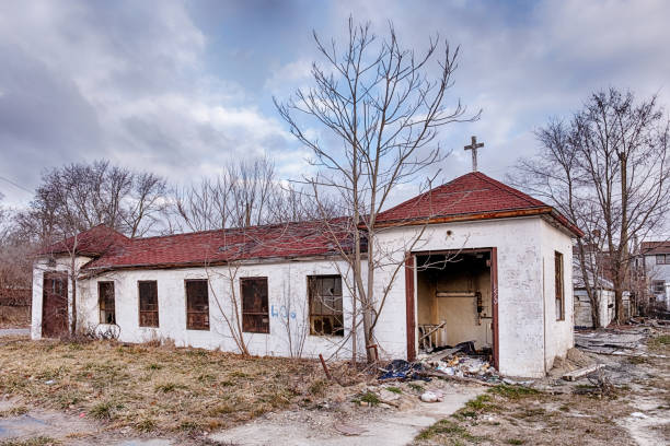 An abandoned building, once part of a church complex, still has a cross standing over part of the structure.