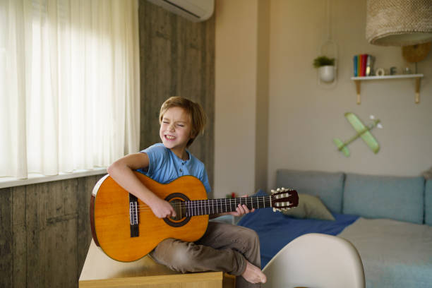 istock Relaxed boy playing guitar at home 2193283943