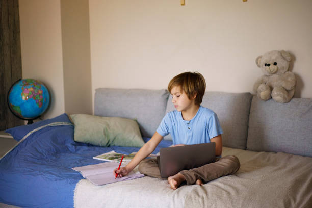 istock A boy writes in a notebook and uses a laptop for homework 2193285199