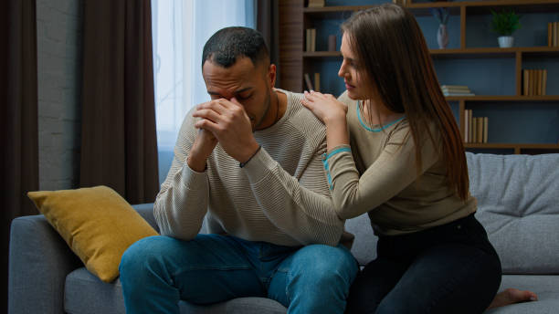istock Desperate sad man sit on sofa upset with bad news complain life problem caring wife support boyfriend. Apologizing woman say sorry hugging annoyed husband diverse couple talking after quarrel conflict 2193285500