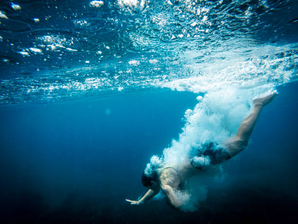 istock Woman diving into deep blue ocean creating bubbles 2193287222