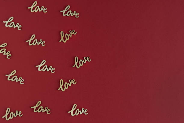 Red cardboard background with word LOVE in wood. Copy space.