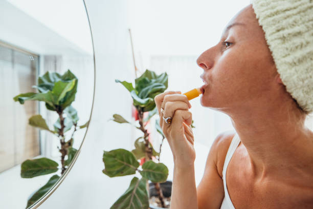 istock Woman Applying Lip Balm in Bathroom with Mirror Reflection 2193290364