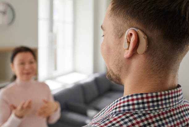 istock Hearing-impaired man uses modern model of hearing aid that is inserted into his ear. 2193290512