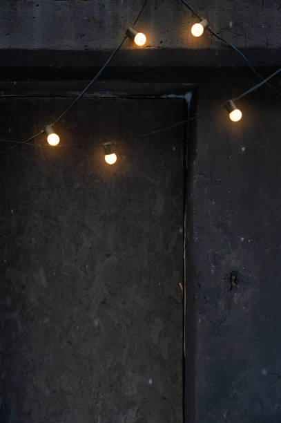 Glowing string lights on a dark concrete wall create a moody and cozy ambiance