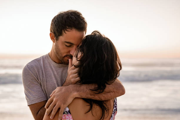 istock Couple sharing a romantic embrace on a beach at dusk 2193291636