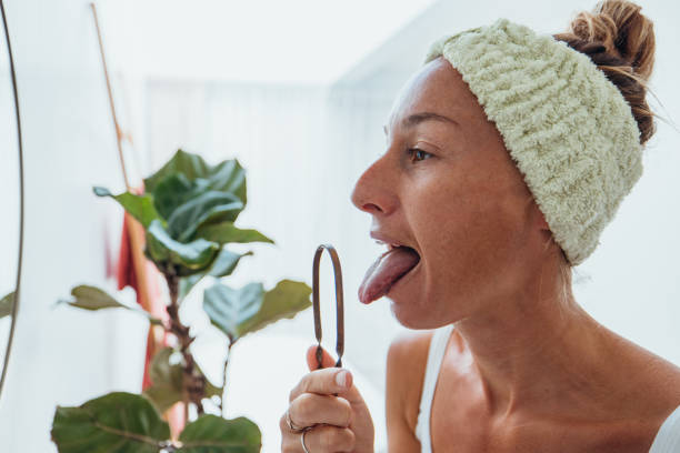 istock Woman Practicing Tongue Cleaning in Modern Bathroom 2193291880