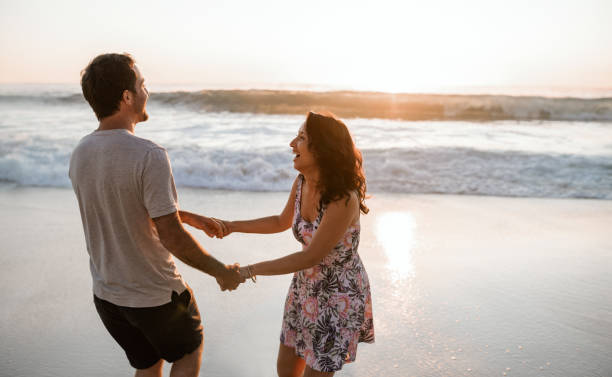 istock Playful young couple having fun at the beach at sunset 2193292238