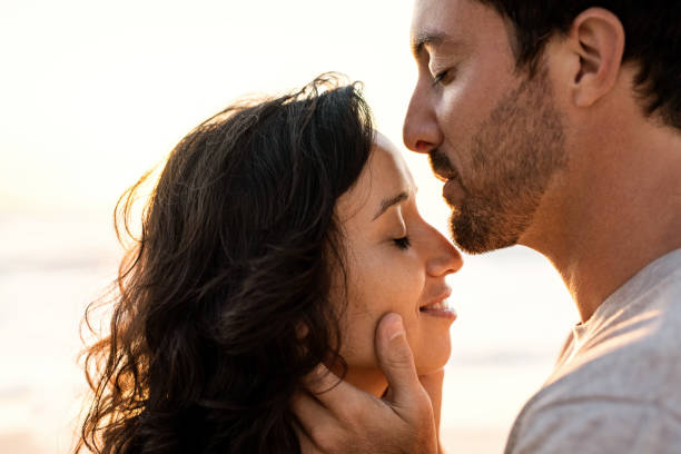 istock Young man kissing his wife on a beach at dusk 2193293365