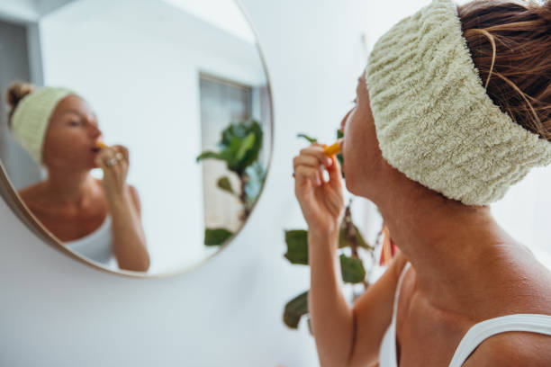 istock Woman Applying Lip Balm in Bathroom with Mirror Reflection 2193293454