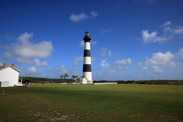 A warm, golden sunset illuminates the Bodie Island Lighthouse at the end of a nearby boardwalk trail
