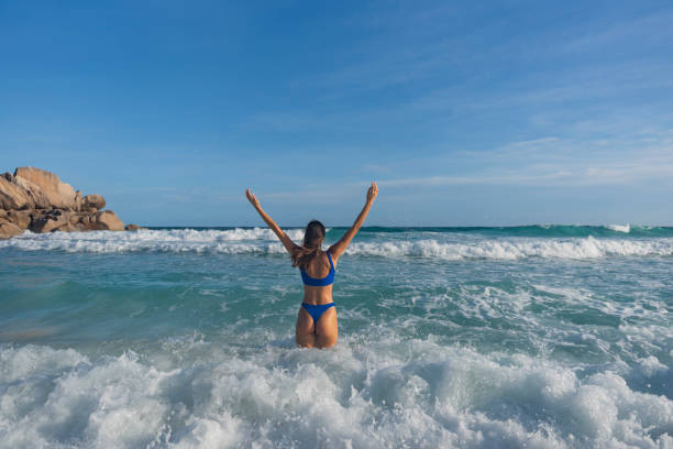Young woman runs into tropical lagoon, Seychelles