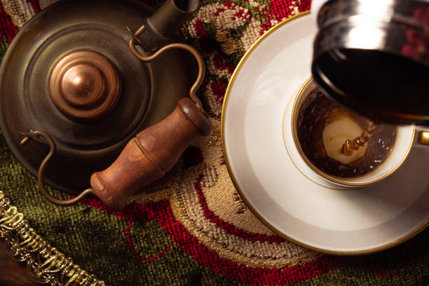 istock Pouring coffee into a cup with vintage kettle on embroidered tablecloth 2193296856