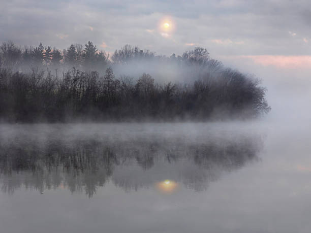 Setting moon over foggy autumn landscape reflected in tranquil steaming river.