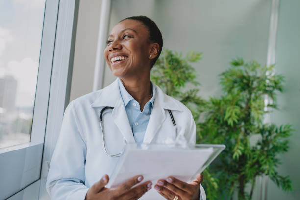 Smiling doctor looking out the window in her office stock photo