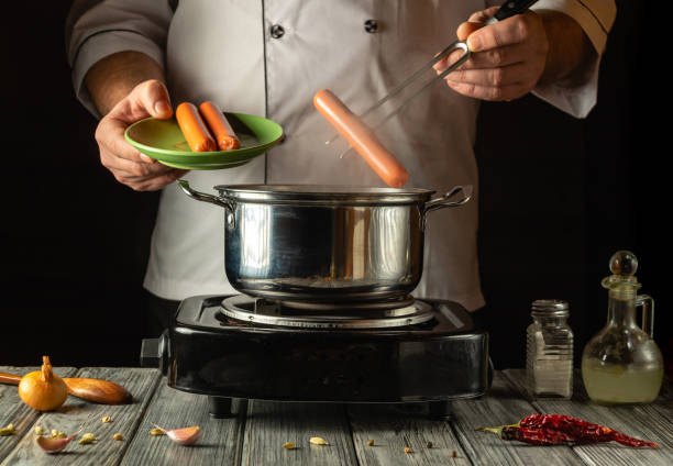istock A chef skillfully drops sausages into a pot of simmering water, surrounded by fresh ingredients. The warm ambiance and careful technique highlight a passion for culinary arts 2193299896