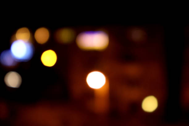 A mesmerizing, out-of-focus depiction of city lights at night. Vibrant orbs of color in various hues—blues, yellows, and whites—blend harmoniously against a dark backdrop, evoking a sense of mystery and allure. This abstract image captures the enchanting beauty of urban nightlife, perfect for enhancing any creative project.