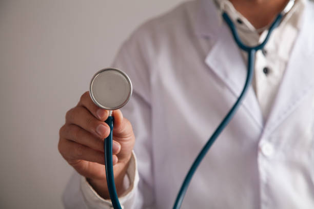 doctor holding stethoscope on light background.