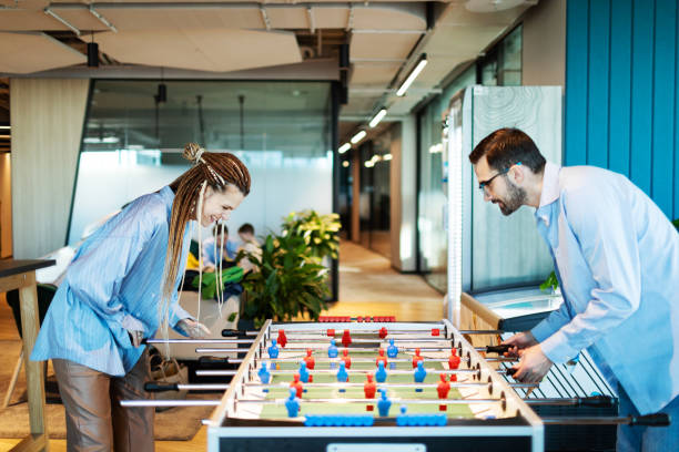 Colleagues relaxing in office playing foosball