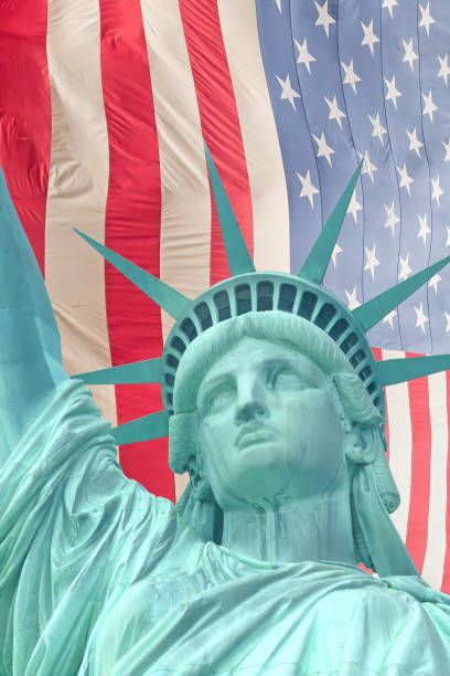 istock Statue of Liberty head with American flag in background. 2193312256