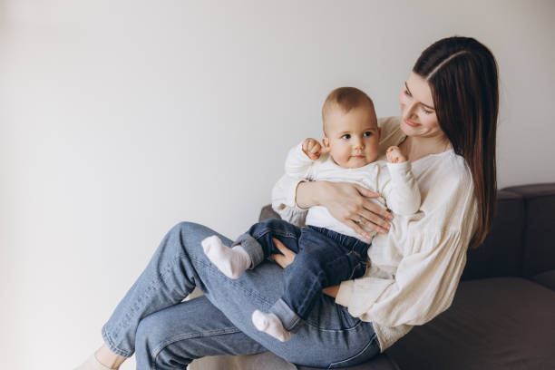 istock Mother holding her baby while sitting on a sofa 2193316559