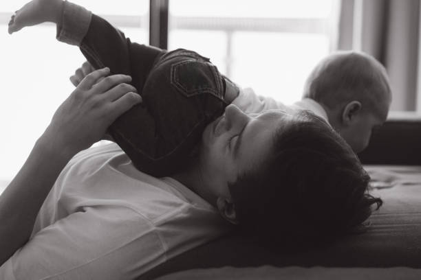 istock Father playing with children on bed in black and white 2193317402