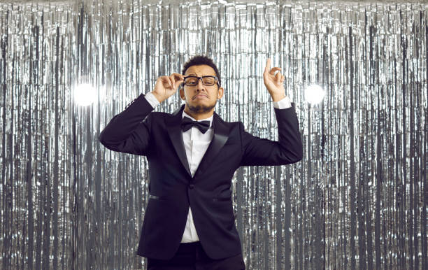 One man only / waist up / front view / looking at camera of 30-39 years old adult handsome people / short hair latin american and hispanic ethnicity male / young men business person / businessman standing / blurred motion in front of black background who is outdoors wearing businesswear / button down shirt / shirt / a suit who is serious / confidence / concentration / night / nightlife / light trail / black color / building exterior / city / city life / downtown district / financial district / urban skyline / skyscraper / street / seattle / washington state
