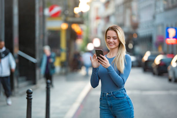 istock Woman Smiling While Using Smartphone on Modern Street 2193323942