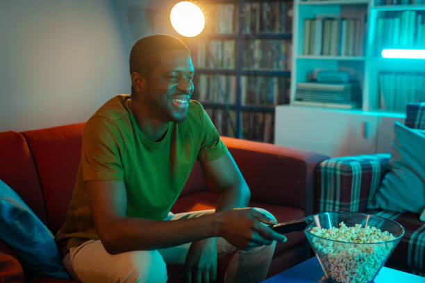 istock Smiling man enjoying a film at home while eating popcorn 2193324104