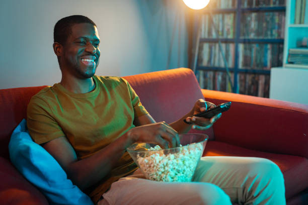 istock Smiling man enjoying a film at home while eating popcorn 2193324112