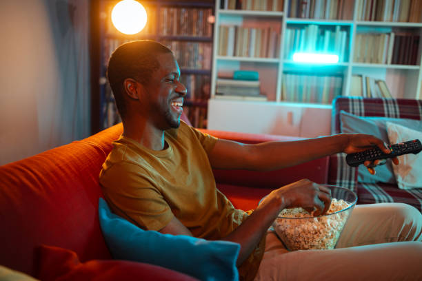 istock Man enjoying popcorn while watching a movie at home in a cozy setting 2193324194