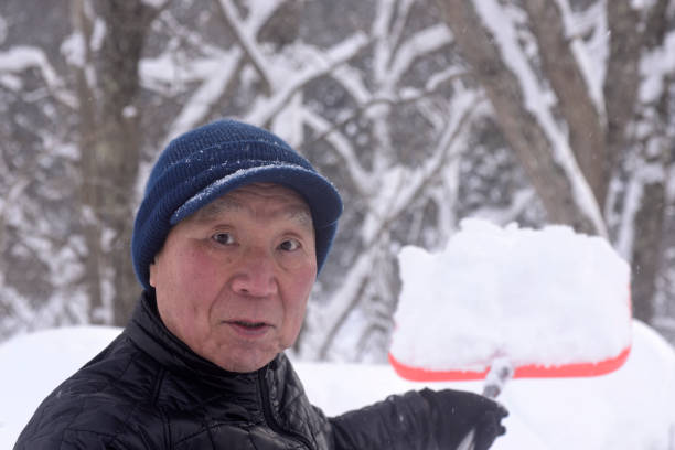 istock An old man clearing snow in a snowy area 2193325132