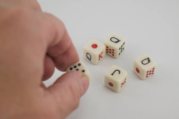 istock Hand taking a poker dice, with 4 other dice on the table 2193325236