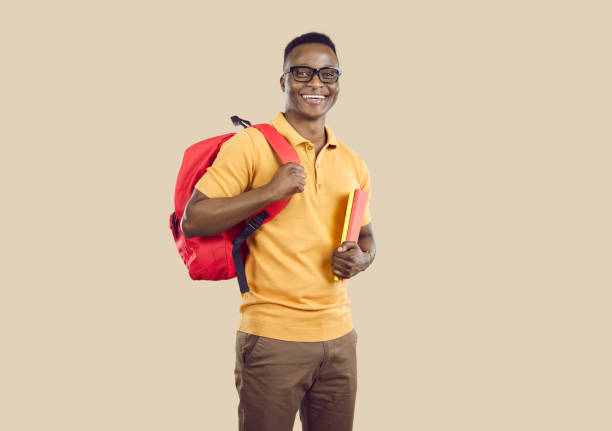 istock Happy African American student with books and backpack standing on beige studio background 2193326808