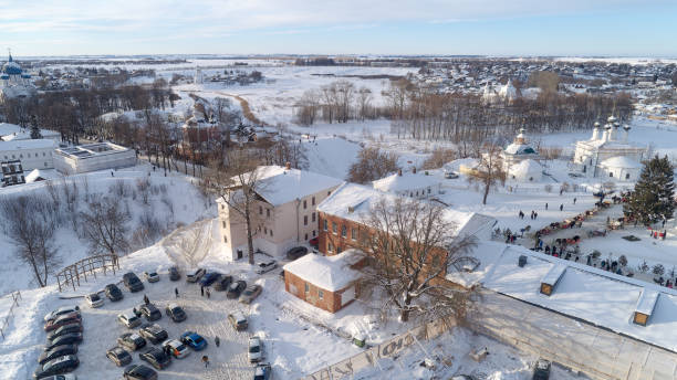 Snowy town with a large building in the center. The building is surrounded by cars and people. The ancient Russian city of Suzdal