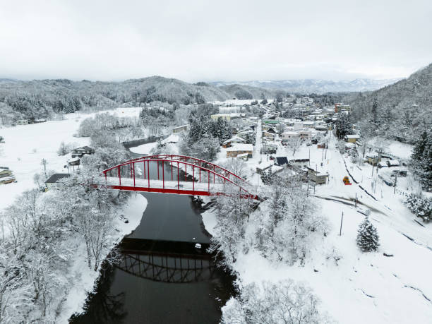High angle view over rural town  in Iwate, North Japan with a red bridge over a river and small town covered in snow.