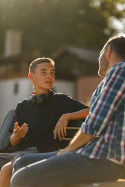 Teenage boy and his father having a heartfelt conversation stock photo