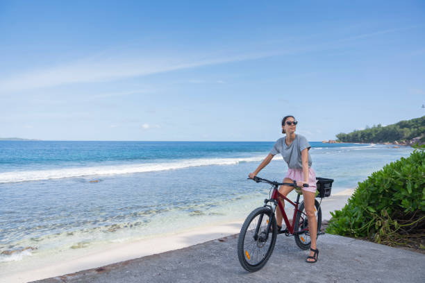 istock Young woman rides bicycle along seaside 2193342032